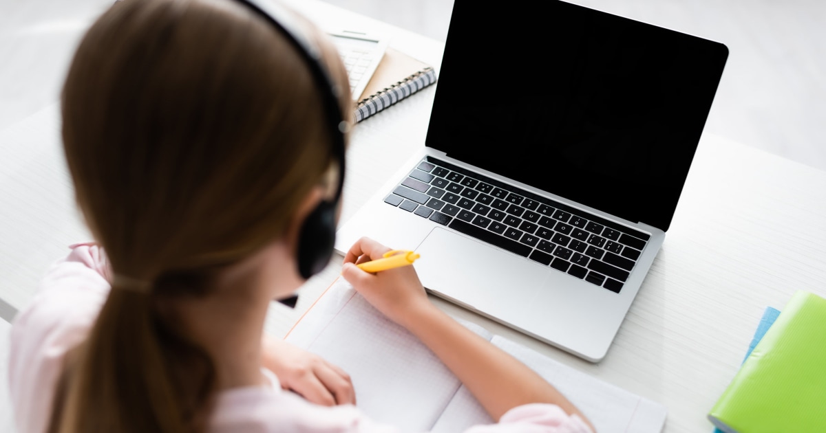 young girl working with laptop and notebook for virtual learning