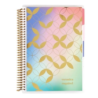 A spiral notebook with a pastels-and-gold geometric print and the name 