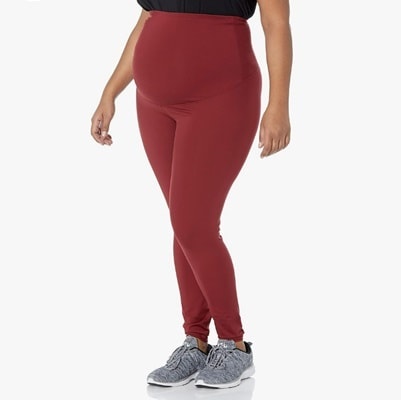 A pregnant woman wearing red leggings and gray sneakers