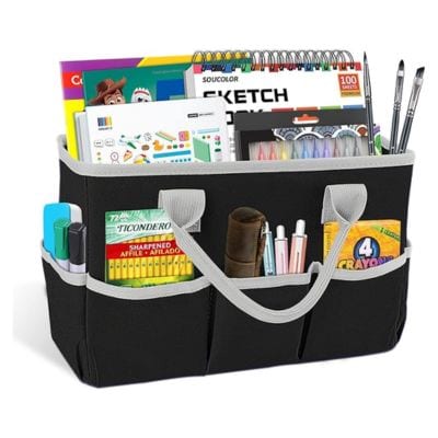 A black tote with several pockets that hold art supplies such as pencils, crayons, and a sketch pad