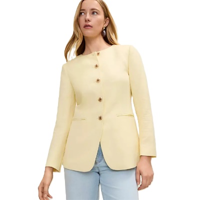 A woman wearing a light yellow collarless jacket and light blue jeans