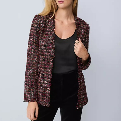 A woman wearing a l long multicolored tweed jacket, black top, and black pants