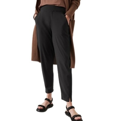 A woman wearing a brown top, long brown cardigan, black ankle pants, and black sandals
