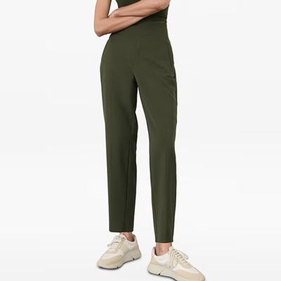 A woman wearing olive green pants and cream-colored sneakers