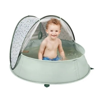 A toddler in a light green kiddie pool filled with water 