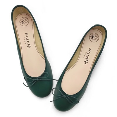 A pair of dark green ballet flats with cream-colored insoles