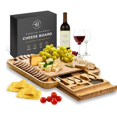 A charcuterie board filled with food, next to a bottle and glass of wine and the gift box