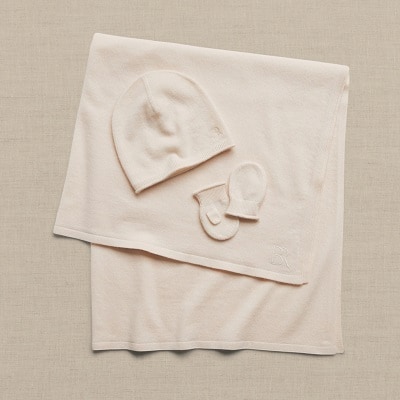 A cream-colored baby blanket, hat, and mittens