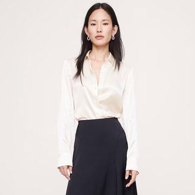 A woman wearing an ivory silk blouse and black skirt