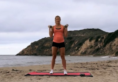 A pregnant woman exercising on a beach