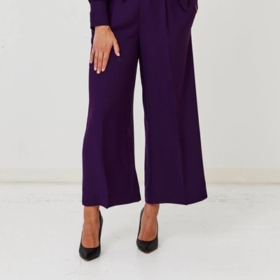 A woman wearing dark purple pants and black heels