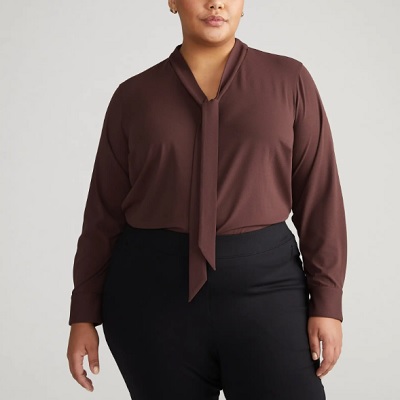 A woman wearing a brown blouse and black pants
