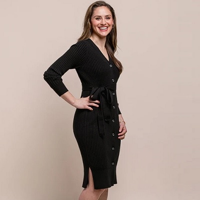 A woman with long brown hair wearing a black button-front dress