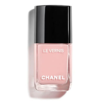 A bottle of Chanel nail polish in a pink shade. The lid is black, and the text on the bottle says CHANEL and LE VERNIS