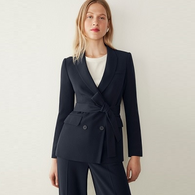 A woman wearing a navy suit and white top