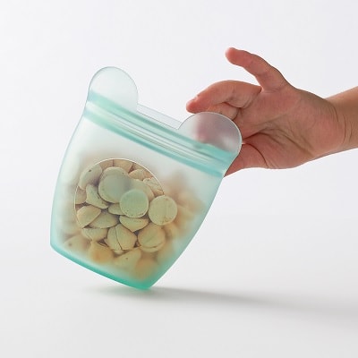 A child's hand holding a green snack container with bear ears