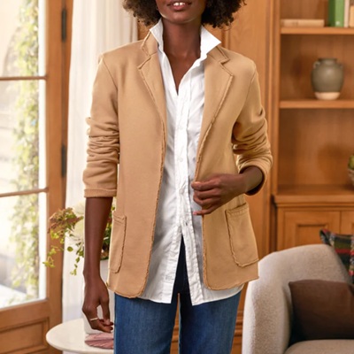 A woman wearing a white polo inner top with beige coat with collar and denim pants