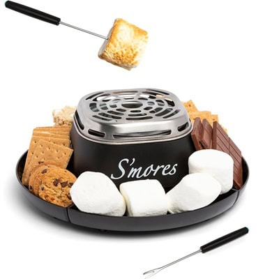 An indoor s'mores maker. It's black and contains graham crackers, marshmallows, and chocolate. A marshmallow is on a stick, being toasted above the heat source.