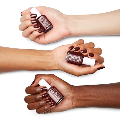 The arms of three women with different skin tones, each holding a bottle of Essie nail polish