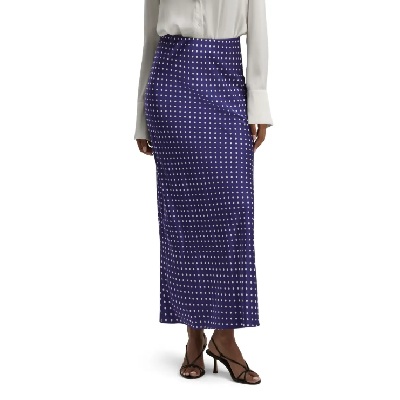 A woman wearing a white blouse and navy polka dot skirt, plus black sandals