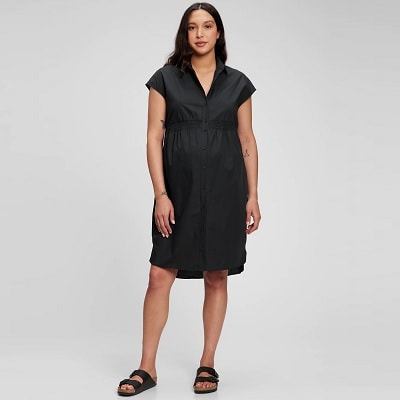A woman with long black hair and a black maternity shirtdress with black sandals