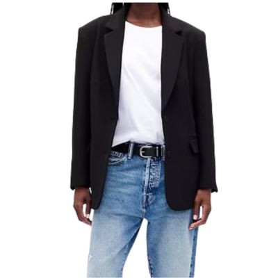 A woman wearing a white top, black blazer, and blue jeans