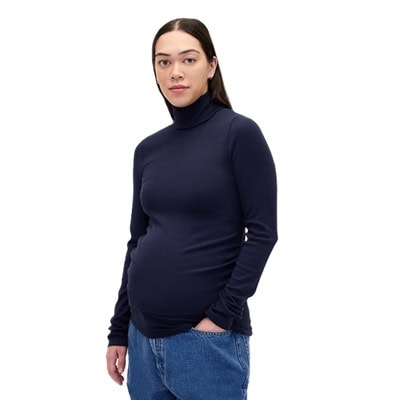 A pregnant woman wearing a navy blue turtleneck and blue jeans