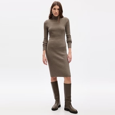 A woman wearing a brown sweater dress and brown boots