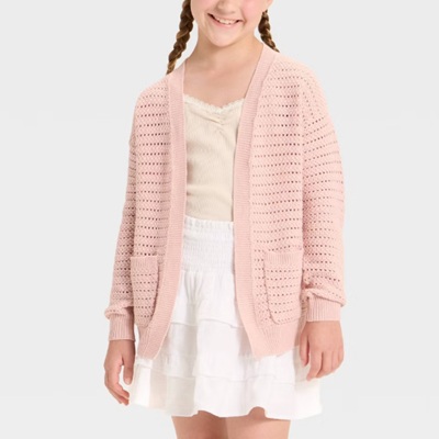 A kid wearing a baby pink knitted cardigan top with dirty white inner top and white skirt