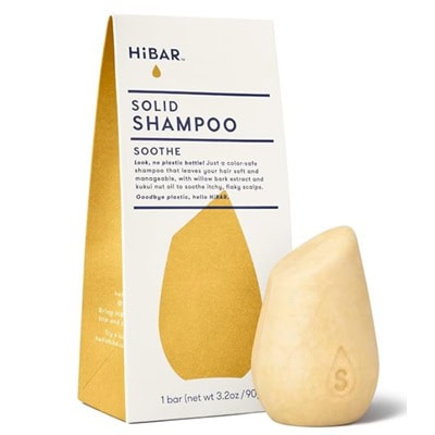 A yellow shampoo bar next to its box, which reads "HiBAR Solid Shampoo