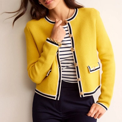 A woman wearing a yellow jacket, striped top, and black pants