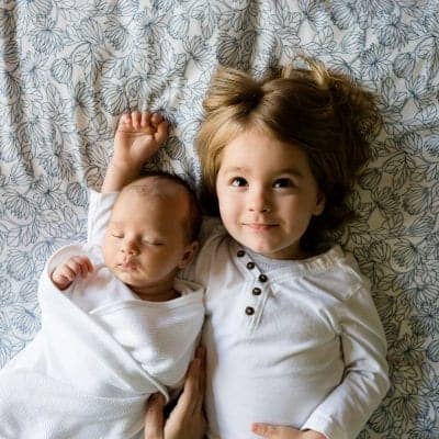 A little girl beside a baby.