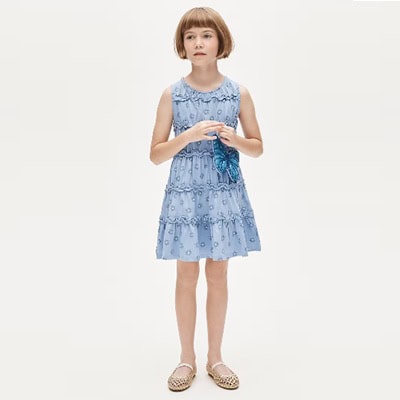 A girl wearing a light-blue tiered-ruffle dress and sandals