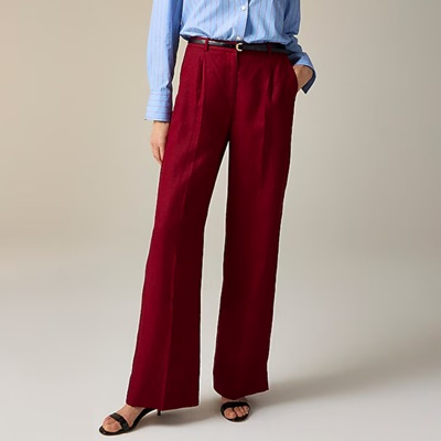 A woman wearing red linen pants, black sandals, and a blue blouse