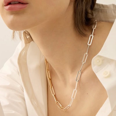 A woman waring a white button-front blouse and a fine chain necklace