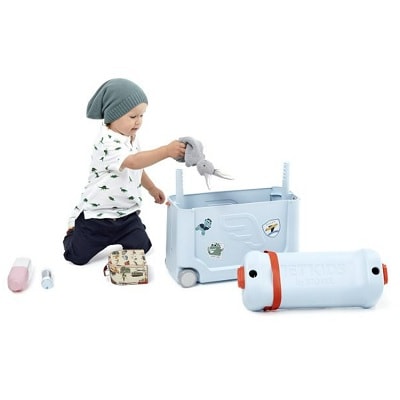 A toddler packing a blue suitcase with a stuffed rabbit and three other items