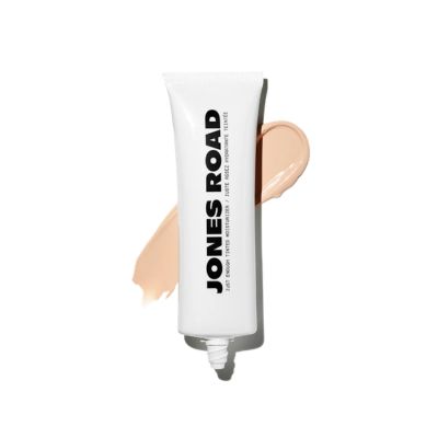 A white tube of Jones Road tinted moisturizer in front of a shade swatch