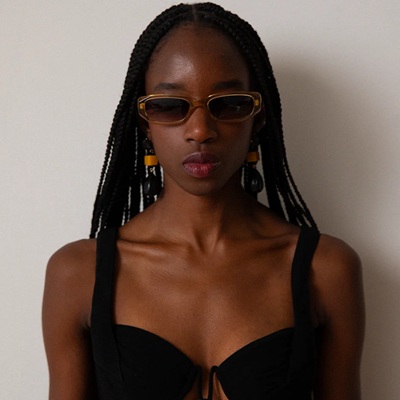 A woman wearing a black swimsuit and gold sunglasses