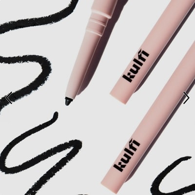 Parts of three peach-colored eyeliner pencils next to scribbled black lines from the liners