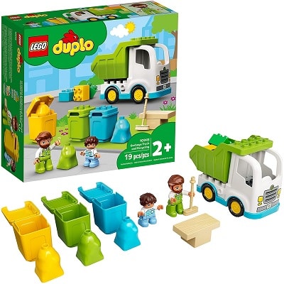 A Lego Duplo set with a garbage truck, two people, figures, three trash bags, a broom, and a table