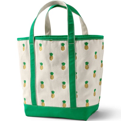 An off-white tote bag with green straps and trim and pineapples all over