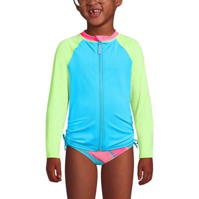 A girl wearing a long-sleeve rash guard in pink, blue, and lime green, with coordinating swimsuit bottom