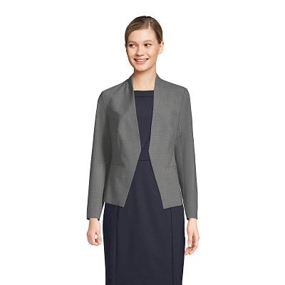 A woman wearing a navy sheath dress with a gray collarless blazer