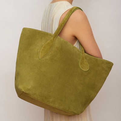 A woman in a pastel striped dress, carrying a green suede tote