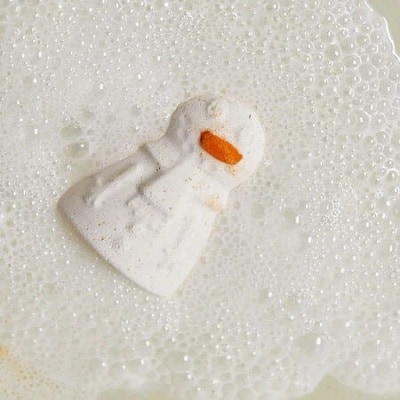 A snowman bath bomb surrounded by soap bubbles