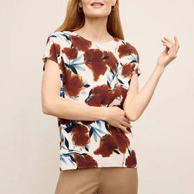 A woman wearing a brown floral printed top with khaki-colored pants