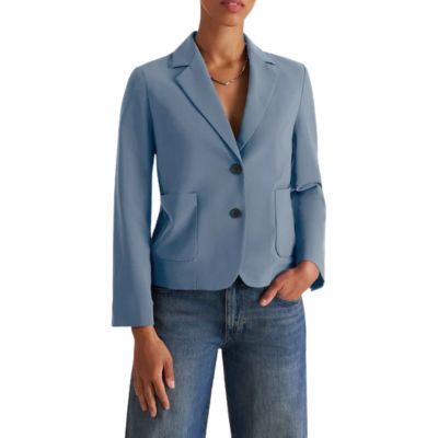 A woman wearing a slate blue blazer, silver necklace, and medium blue jeans