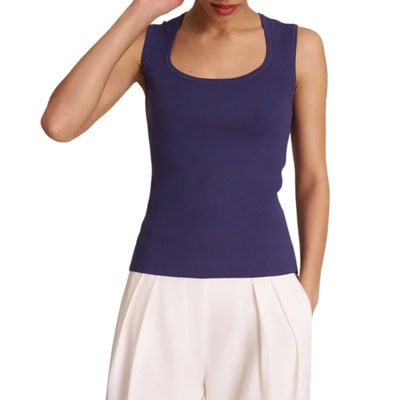 A woman wearing a navy tank and flowy, ivory pants