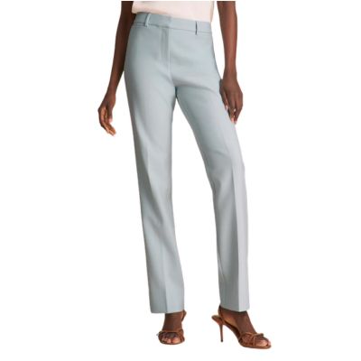 The lower half of a woman who is wearing light blue pants and brown strappy sandals