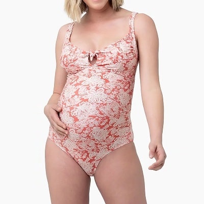 A pregnant woman wearing a coral-and-white swimsuit